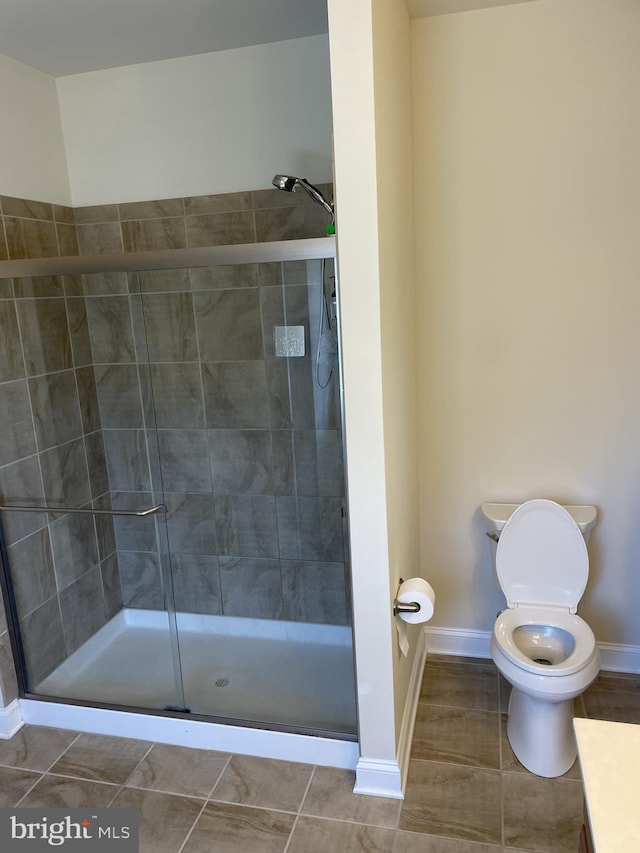 bathroom featuring toilet and a shower with shower door