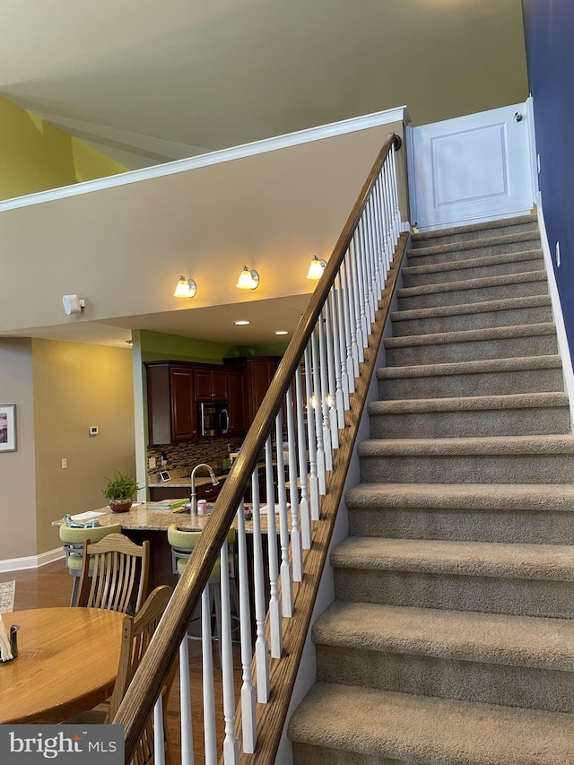 stairway with sink and hardwood / wood-style flooring