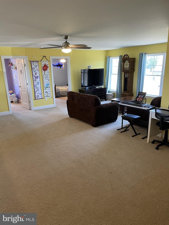 living room with a wealth of natural light, ceiling fan, and light carpet