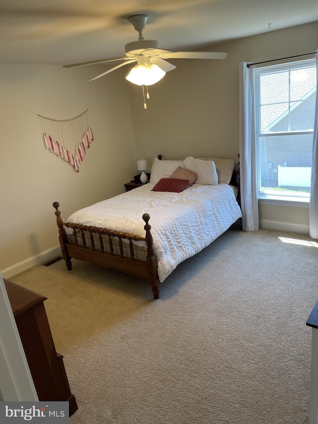 carpeted bedroom featuring multiple windows and ceiling fan