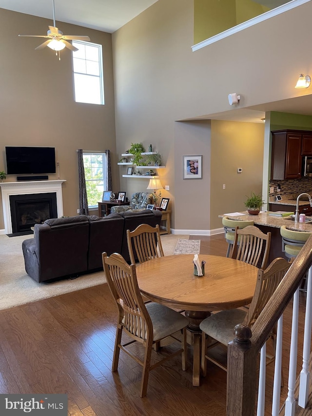 dining space with ceiling fan, wood-type flooring, a towering ceiling, and sink