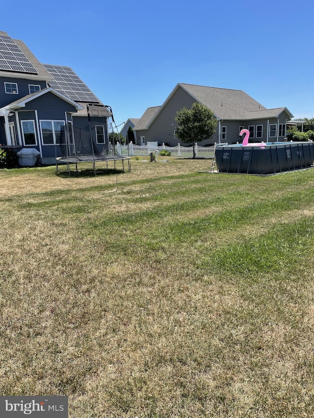 view of yard featuring a fenced in pool and a trampoline