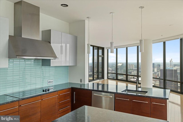 kitchen featuring stainless steel dishwasher, dark stone counters, black electric cooktop, wall chimney range hood, and hanging light fixtures