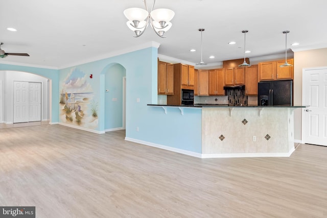 kitchen with decorative light fixtures, light hardwood / wood-style flooring, black appliances, and backsplash