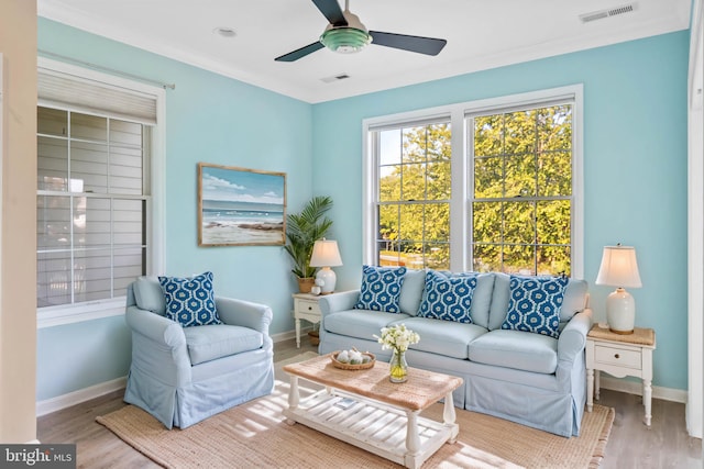 living room with wood-type flooring, crown molding, and ceiling fan