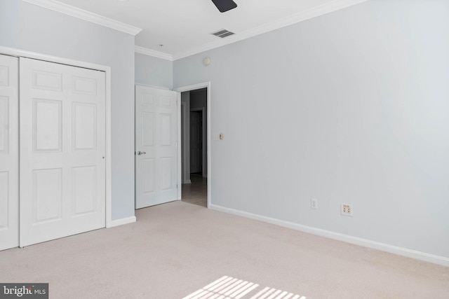 unfurnished bedroom featuring a closet, carpet, crown molding, and ceiling fan