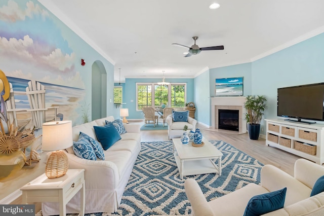 living room featuring light hardwood / wood-style floors, ornamental molding, a tile fireplace, and ceiling fan