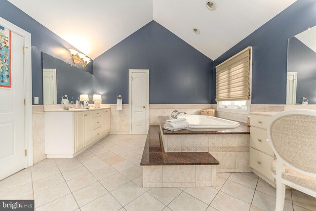 bathroom with tile patterned floors, tiled tub, vanity, and high vaulted ceiling