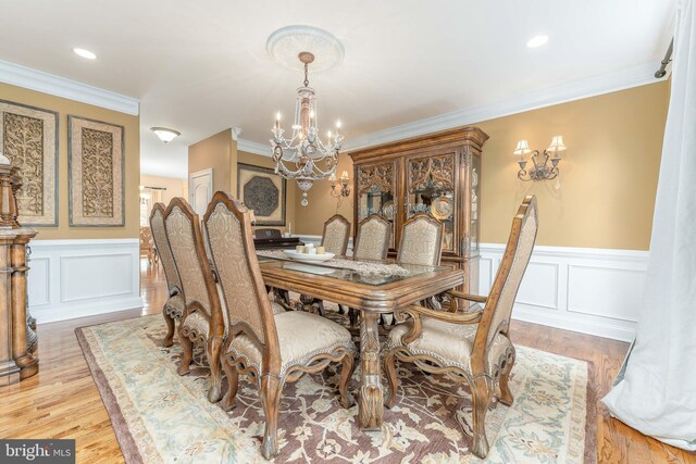 dining room featuring light wood-type flooring, crown molding, and a notable chandelier