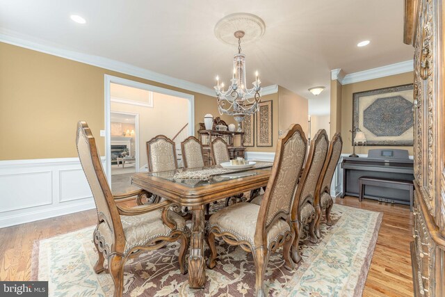 dining space with an inviting chandelier, light hardwood / wood-style floors, and ornamental molding