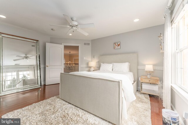 bedroom featuring dark hardwood / wood-style floors and ceiling fan with notable chandelier