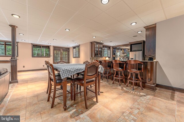 dining room with a paneled ceiling and bar