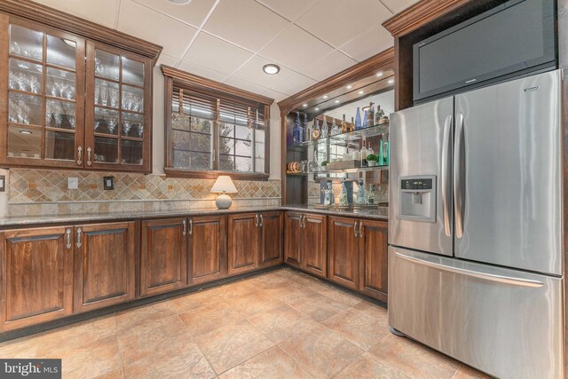 kitchen with a drop ceiling, tasteful backsplash, stainless steel fridge with ice dispenser, dark stone countertops, and light tile patterned flooring