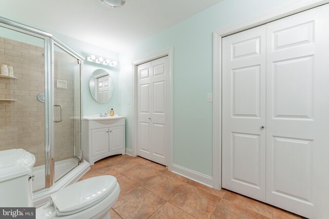 bathroom with tile patterned floors, vanity, a shower with shower door, and toilet