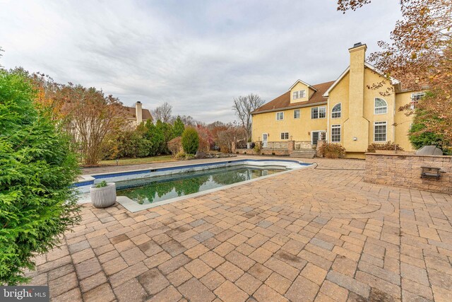 view of pool with an outdoor kitchen and a patio area