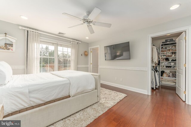 bedroom with ceiling fan, dark hardwood / wood-style floors, a spacious closet, and a closet