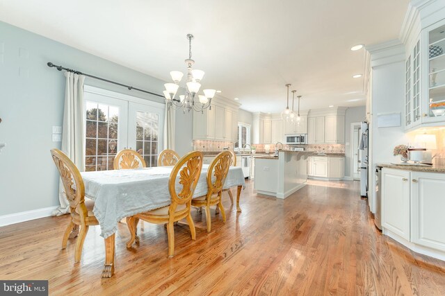 dining room featuring french doors, light wood-type flooring, an inviting chandelier, and sink