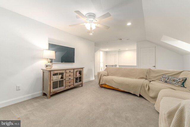 carpeted living room with vaulted ceiling with skylight and ceiling fan