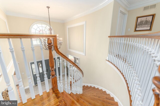 stairway featuring hardwood / wood-style flooring, an inviting chandelier, and crown molding