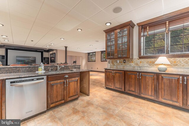 kitchen with tasteful backsplash, stainless steel dishwasher, sink, dark stone countertops, and light tile patterned flooring