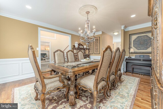 dining space featuring a notable chandelier, light hardwood / wood-style floors, and crown molding