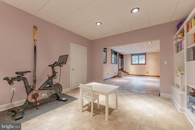 workout area with a paneled ceiling and light carpet