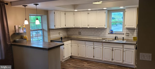 kitchen with kitchen peninsula, backsplash, a wealth of natural light, sink, and white cabinets