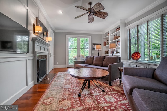 living room with a fireplace, wood-type flooring, a wealth of natural light, and ceiling fan