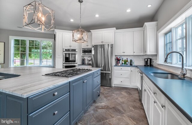 kitchen featuring decorative light fixtures, blue cabinets, sink, and appliances with stainless steel finishes