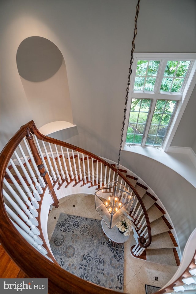 stairs featuring tile patterned flooring and a chandelier