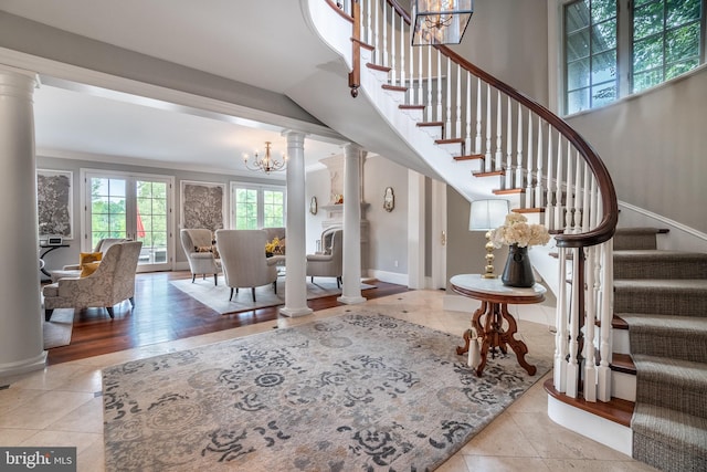 tiled entryway with a chandelier, decorative columns, and ornamental molding