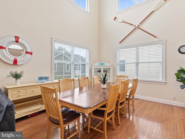 dining space with hardwood / wood-style flooring and a towering ceiling