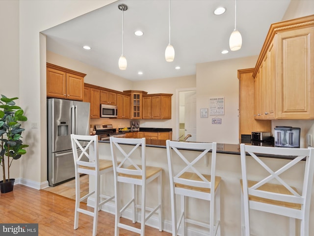 kitchen featuring a breakfast bar, appliances with stainless steel finishes, kitchen peninsula, and hanging light fixtures