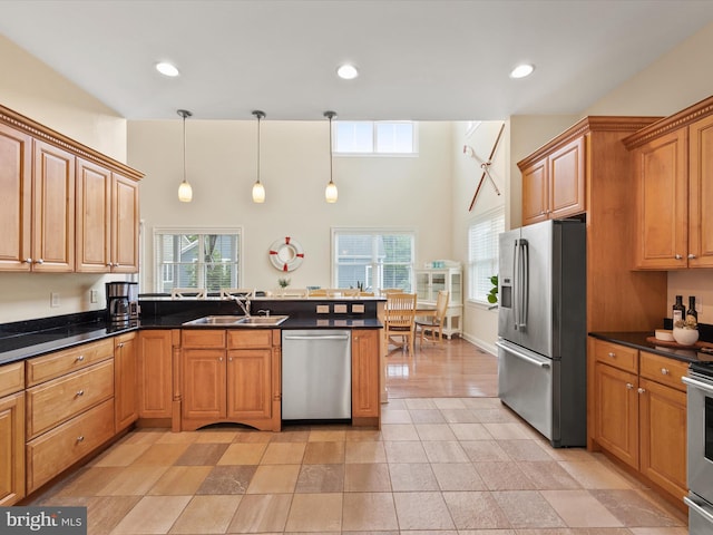 kitchen with kitchen peninsula, sink, stainless steel appliances, and decorative light fixtures