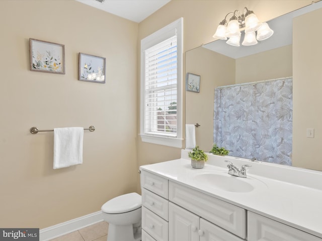 bathroom with tile patterned floors, vanity, a healthy amount of sunlight, and toilet