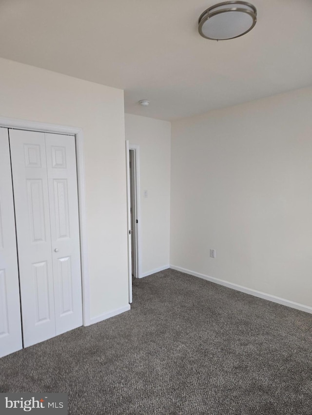 unfurnished bedroom with dark carpet and a closet