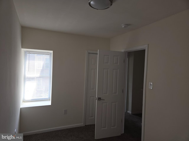 unfurnished bedroom featuring dark carpet and a closet