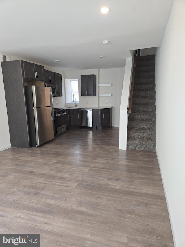 kitchen with appliances with stainless steel finishes, sink, and light hardwood / wood-style floors