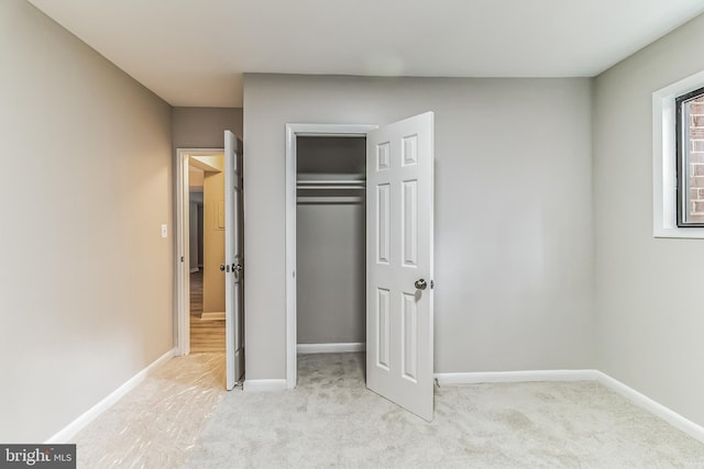 unfurnished bedroom with a closet and light colored carpet