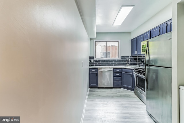 kitchen featuring backsplash, light hardwood / wood-style floors, sink, appliances with stainless steel finishes, and blue cabinets