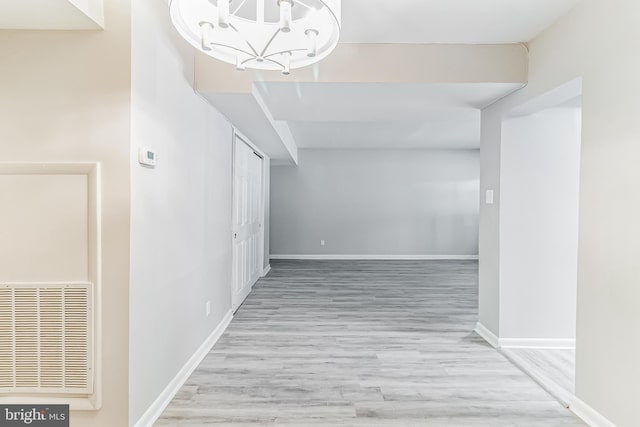 corridor with light hardwood / wood-style floors and a notable chandelier