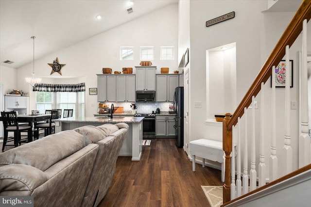 kitchen featuring light stone countertops, stainless steel appliances, backsplash, hanging light fixtures, and gray cabinets