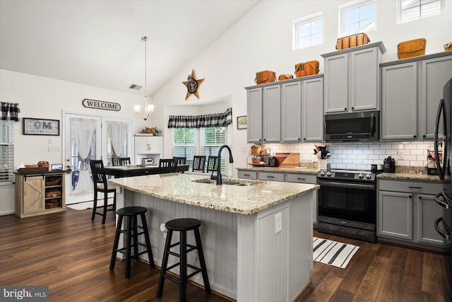 kitchen with sink, pendant lighting, a center island with sink, and range with electric cooktop