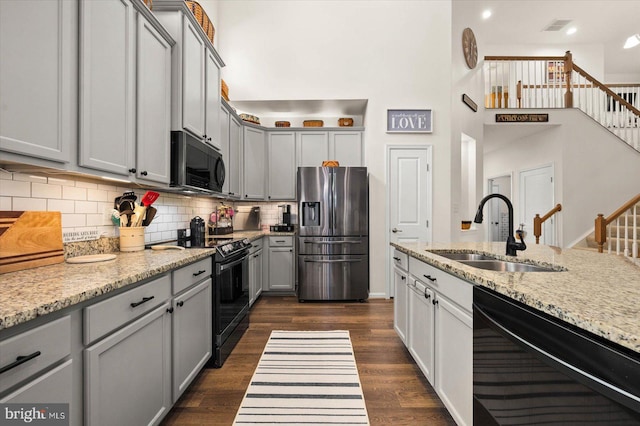 kitchen featuring light stone counters, sink, black appliances, and gray cabinets