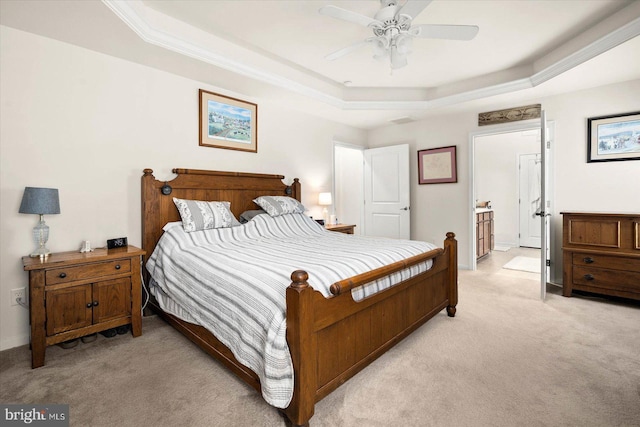 bedroom with ceiling fan, ensuite bathroom, light colored carpet, and a raised ceiling