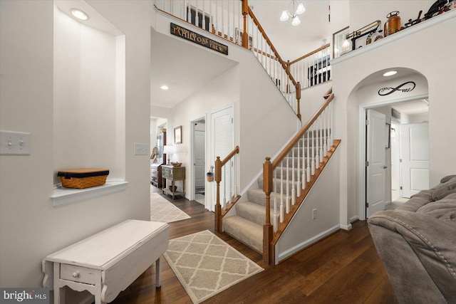 stairway with hardwood / wood-style flooring and a towering ceiling