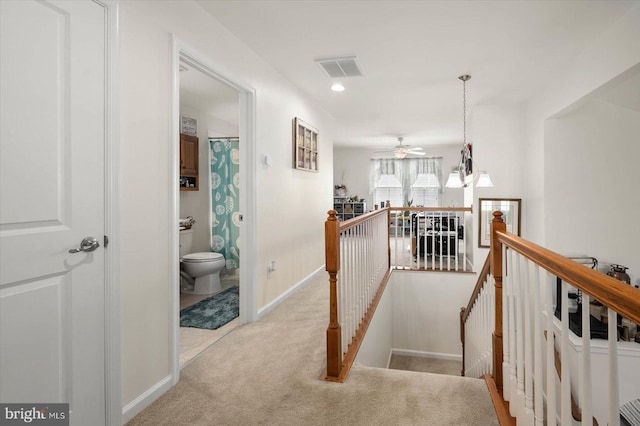 hall featuring light carpet and a notable chandelier