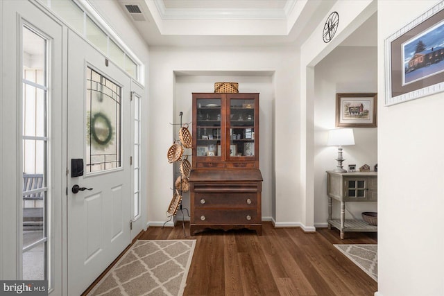 foyer entrance featuring plenty of natural light, a tray ceiling, dark hardwood / wood-style floors, and crown molding