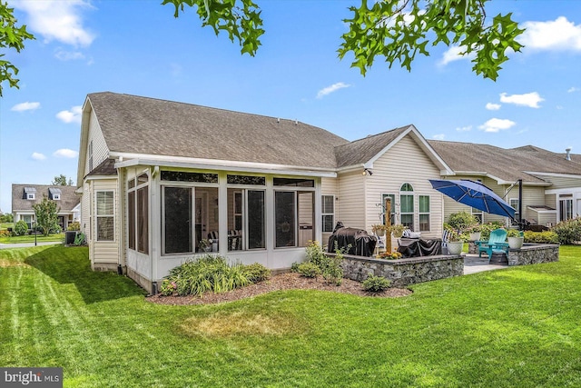 rear view of property with a lawn, a patio area, and a sunroom