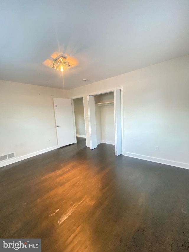 unfurnished bedroom with a closet, visible vents, and baseboards